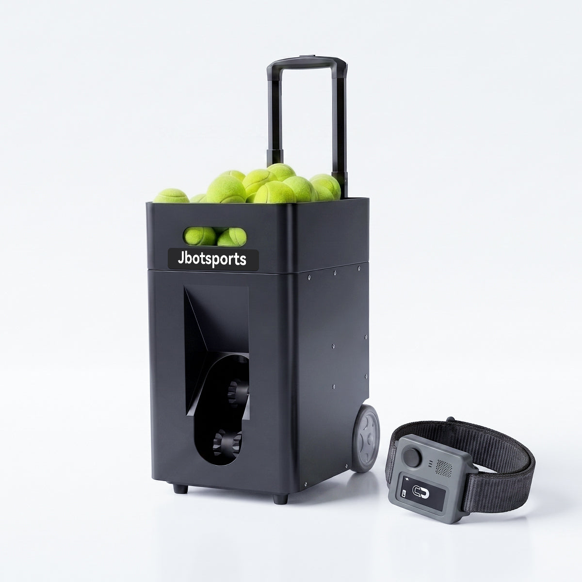 Studio product photo of black Jbotsports JT-02 Pro portable trolley tennis ball machine with retractable pull handle, fully loaded yellow tennis balls inside top hopper, transparent dual-wheel ball outlet window; matching grey voice control smart wristband placed on lower right, clean pure white reflective background for e-commerce display