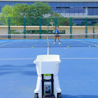 Tennis Ball Machine in Use - Player Practicing with Automatic Tennis Feeder on Outdoor Court
